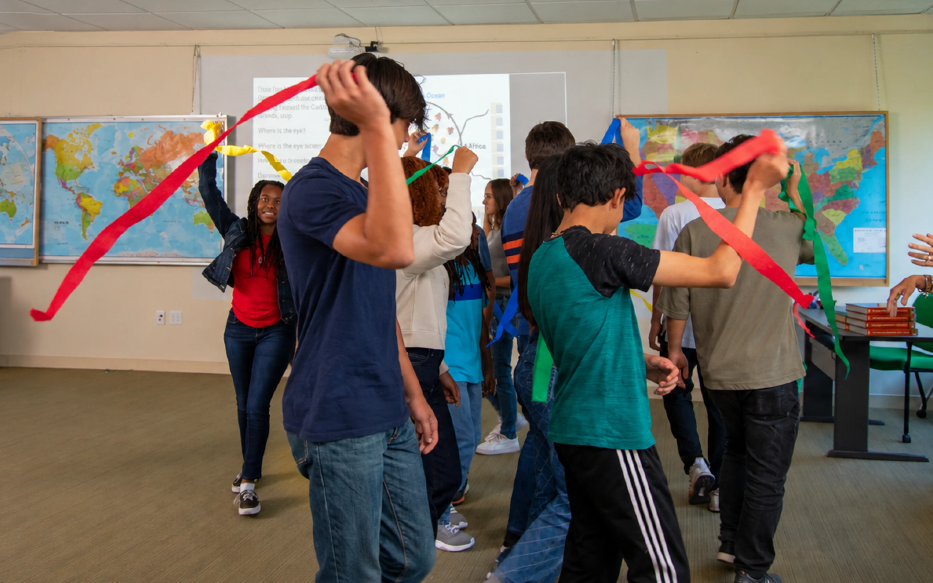A group of students in a classroom hold colorful ribbons while moving in a circle.