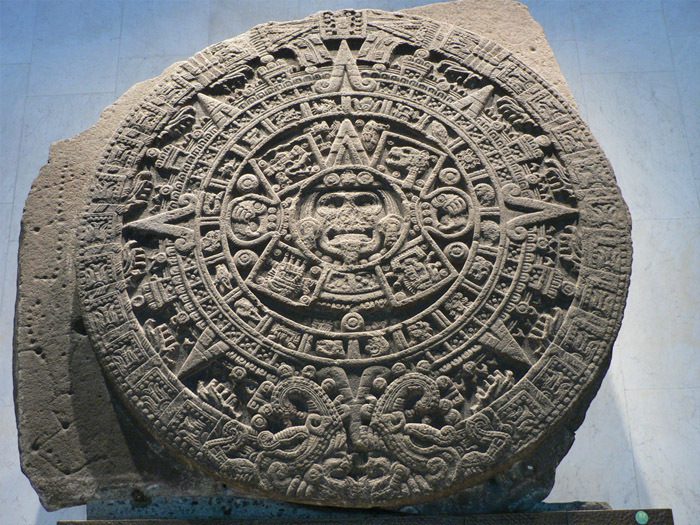 Aztec Sun Stone with intricate carvings, circular design, and detailed symbols, displayed on a flat surface.