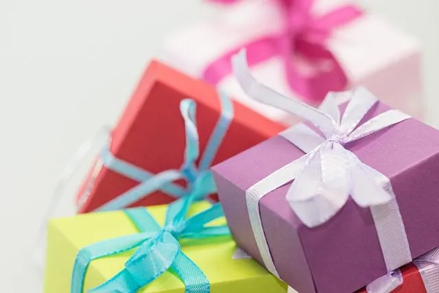 Four colorful gift boxes with blue, white, and pink ribbons stacked close together on a light background.