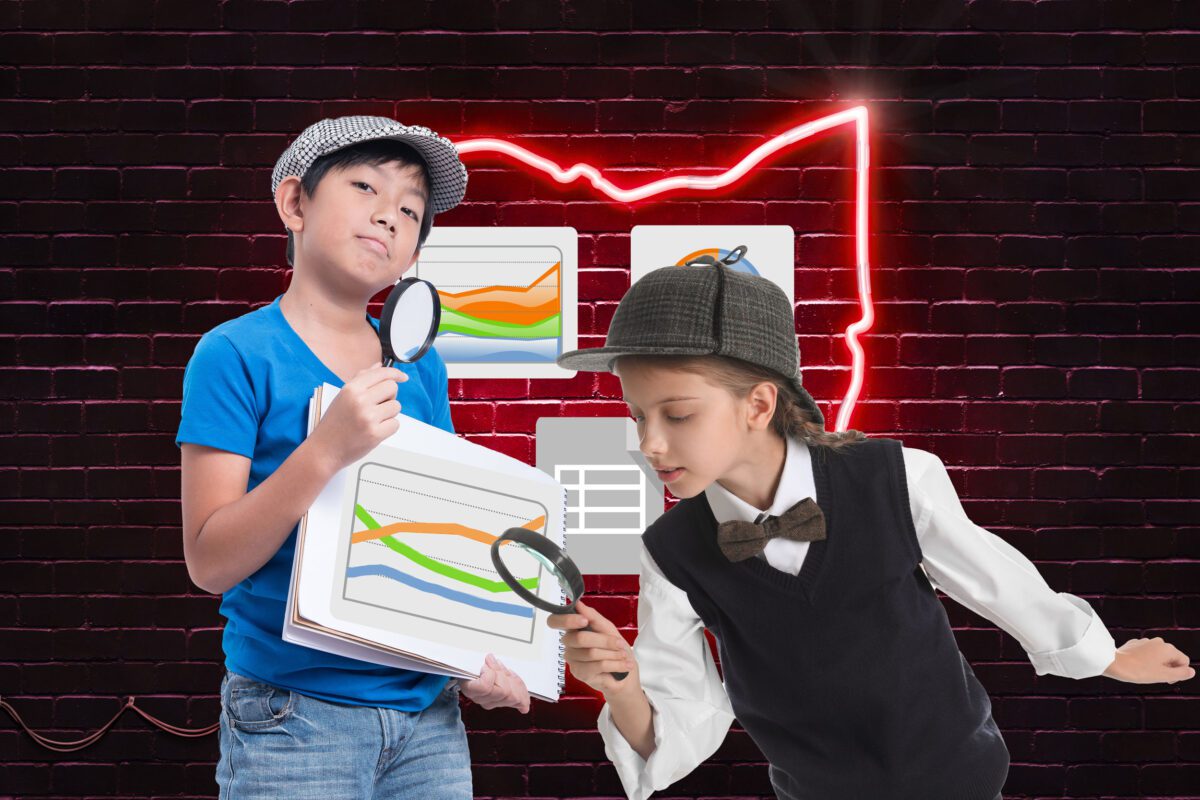 Two kids with magnifying glasses analyzing charts, standing in front of a neon outline of Ohio on a brick wall.