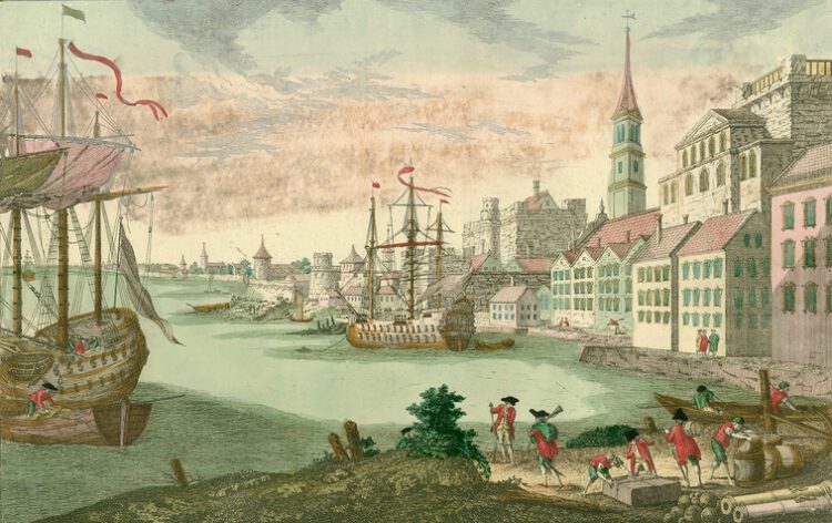 Historic harbor scene with sailing ships, city buildings, and people working near the waterfront, wearing colonial attire.